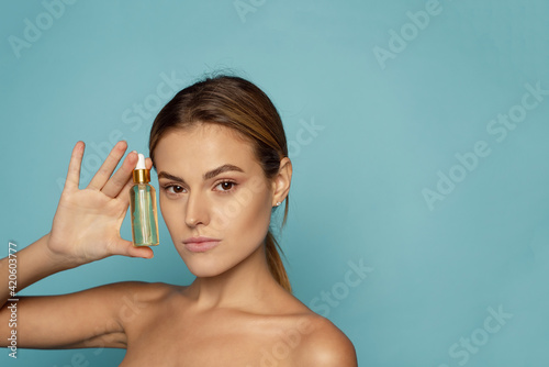 A beautiful young woman moisturizes her skin with a serum. Caring for the skin