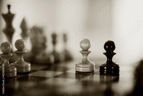 Two pawns - black and white. Wooden chess pieces on the chessboard.
