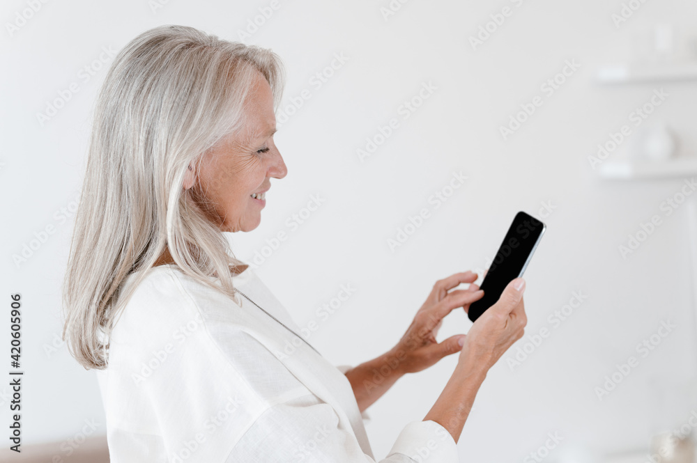 Happy gray haired woman browsing smartphone Happy gray haired woman browsing smartphone