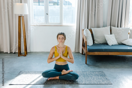 Barefoot female meditating on mat in morning