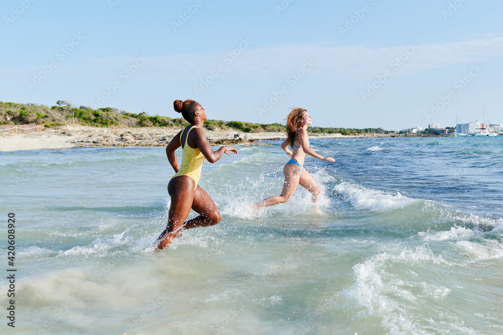 Two women running into the ocean Two women running into the ocean