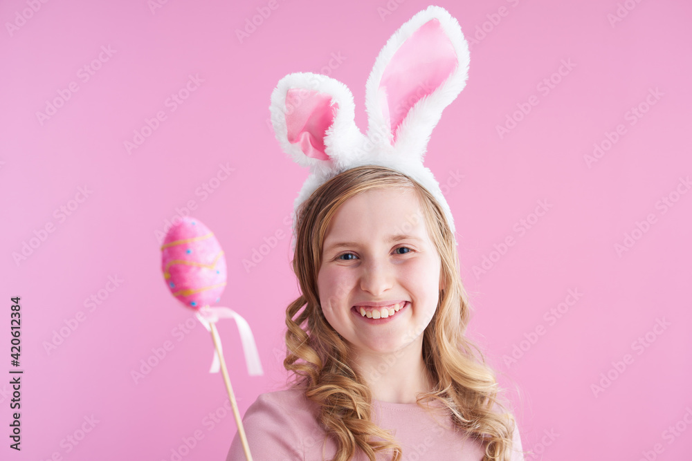 smiling stylish child with long wavy blond hair on pink