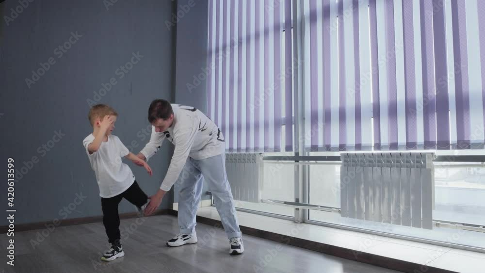 Little boy in white t-shirt dances breakdance with his teacher together Little boy in white t-shirt dances breakdance with his teacher together