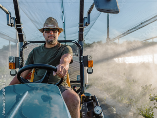 Farmer driving irrigating tractor towards camera photo