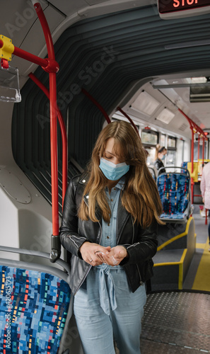 Woman In Public Transport Wearing Surgical Mask Using Hand Sanitizer. photo