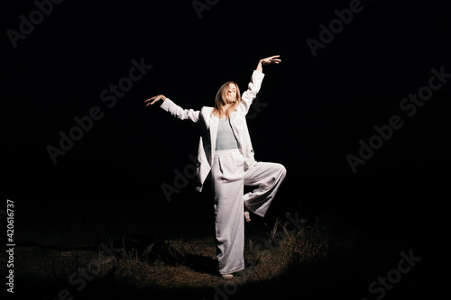 Woman in suit dancing in darkness photo