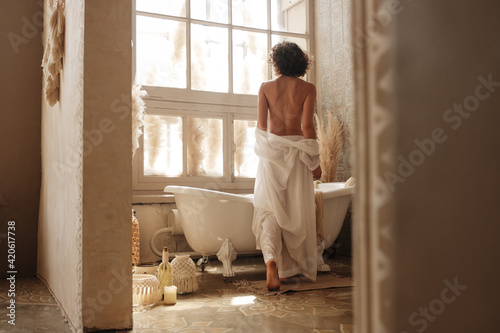 Anonymous woman looking out window in bathroom