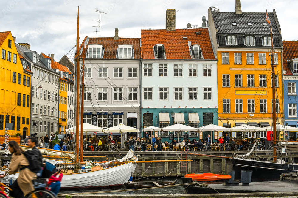 Crowded cafes and shops on an overcast autumn day on the 17th century waterfront canal Nyhavn in Copenhagen, Denmark.