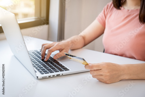 Young Asian consumer woman hand holding a credit card, Ready to spending pay online shopping according to discount products via smartphone and laptop from home