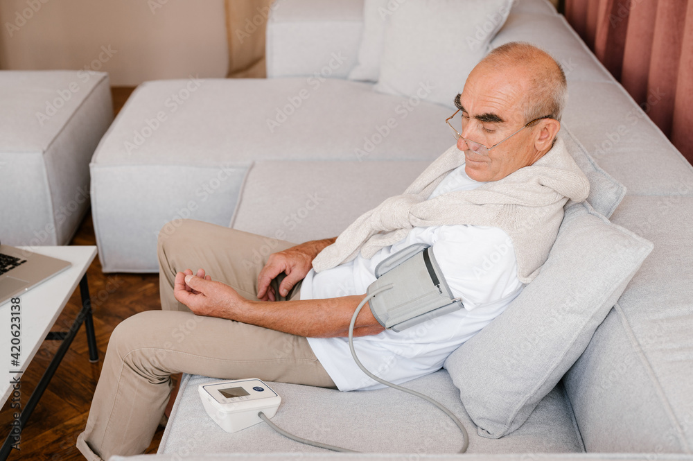 Senior man measuring blood pressure at home Senior man measuring blood pressure at home