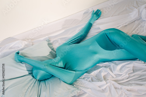 Anonymous person in odd colorful wear lying on bed