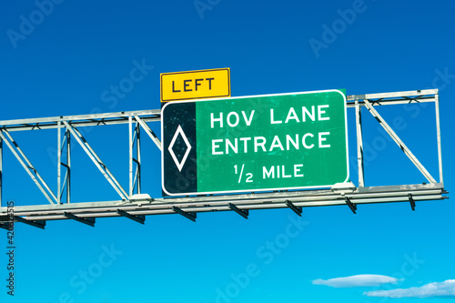 HOV lane entrance road sign. Blue sky.