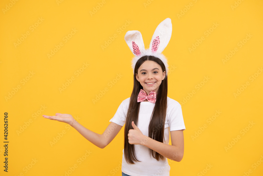 child girl in bunny ears and bow tie presenting product or shopping sales, copy space, happy easter. child girl in bunny ears and bow tie presenting product or shopping sales, copy space, happy easter.