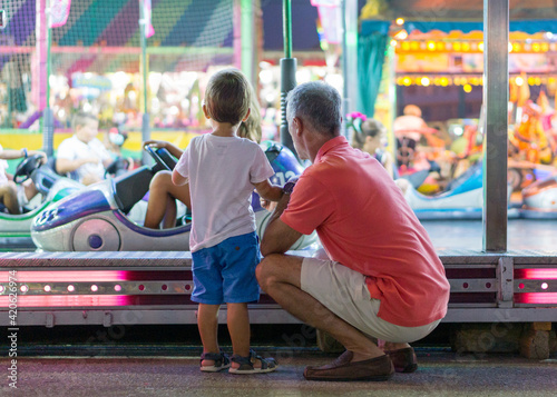 Grandfather with his grandson watching a fairground ride