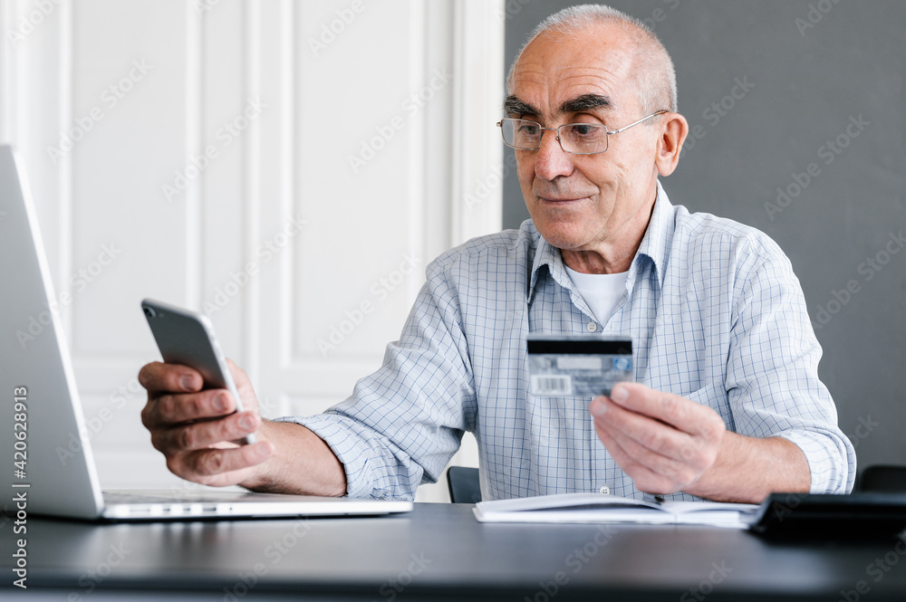 Senior man paying online with smartphone and credit card Senior man paying online with smartphone and credit card