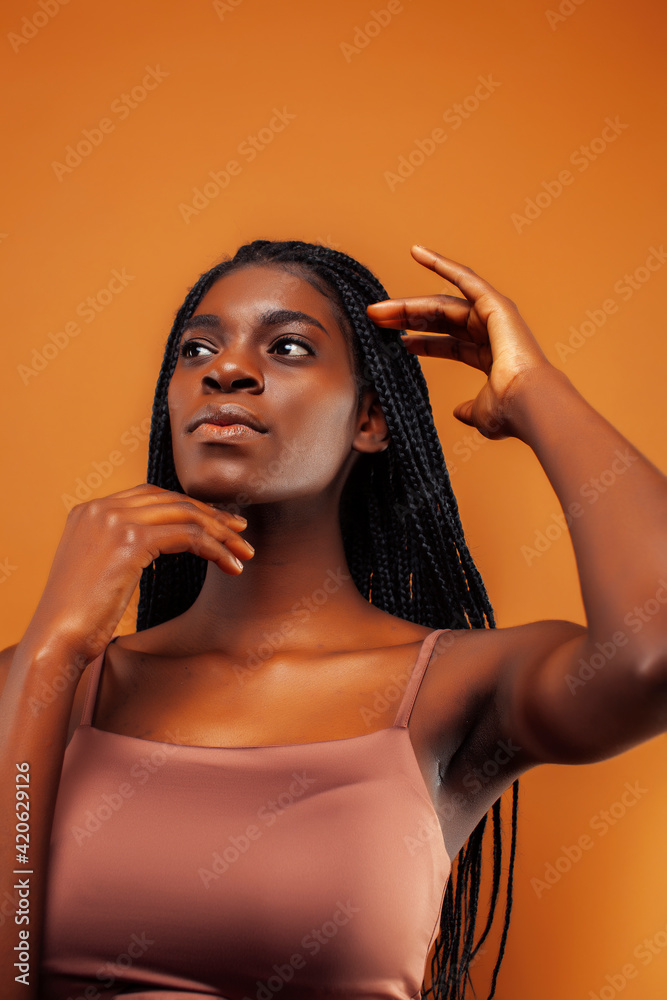 Obraz premium pretty young african american woman with braids posing cheerful gesturing on brown background, lifestyle people concept