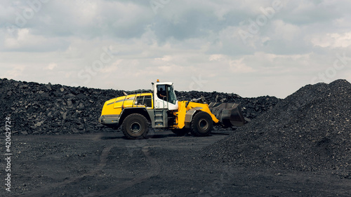 Yellow bucket loader is working busy loading coal. Extraction of minerals.