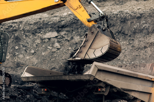 Excavator loads coal into the back of a heavy mining dump truck. Open pit coal mining.