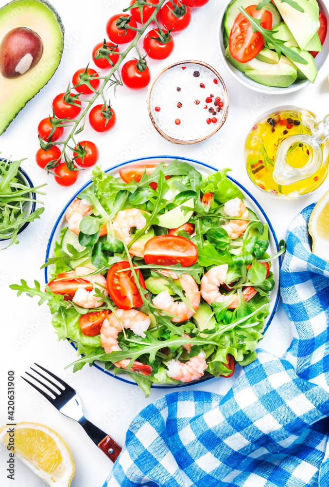 Fresh shrimp salad with tomatoes, lettuce, arugula, avocado, cucumber and lemon dressing on white background. Healthy eating, clean food concept. Top view Fresh shrimp salad with tomatoes, lettuce, arugula, avocado, cucumber and lemon dressing on white background. Healthy eating, clean food concept. Top view