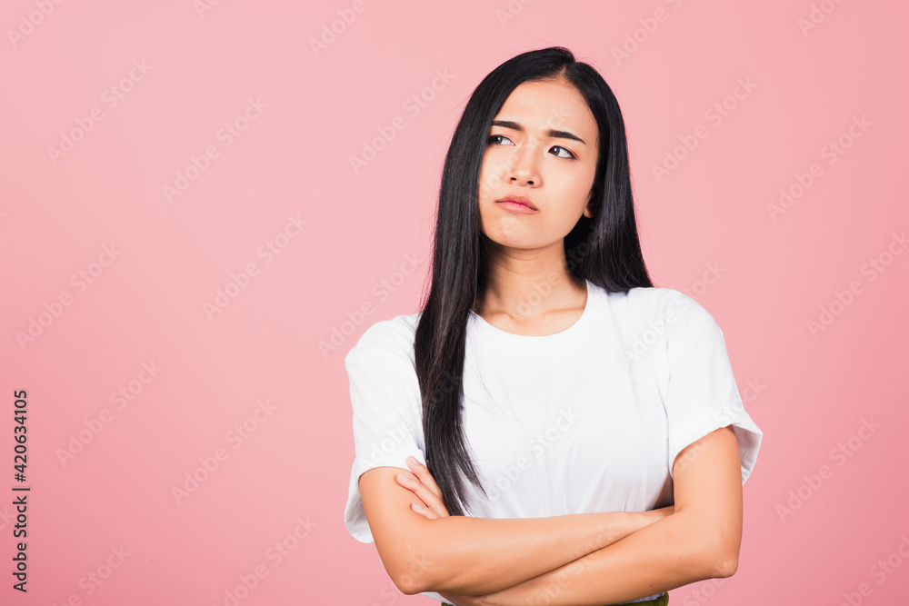 Asian happy portrait beautiful cute young woman standing with crossed arms angry and mad raising fist frustrated and furious while shouting with anger isolated, studio shot on pink background Asian happy portrait beautiful cute young woman standing with crossed arms angry and mad raising fist frustrated and furious while shouting with anger isolated, studio shot on pink background