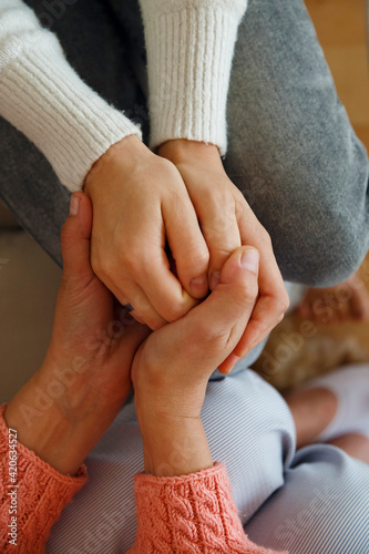 Crop mother holding hands of daughter gently