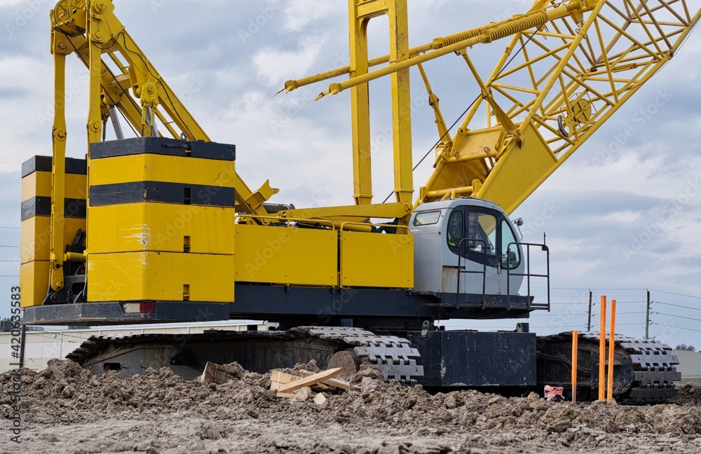 Crawler crane on construction site yellow machine deck counterweight and treads, heavy duty engineering transport machinery building contractor. Crawler crane on construction site yellow machine deck counterweight and treads, heavy duty engineering transport machinery building contractor.