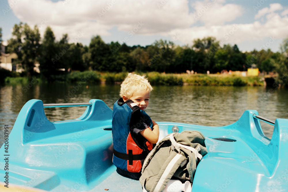 Toddler boy with life jacket in a pedalo boat enjoying summer