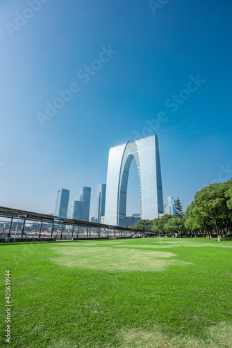The modern skyline in Suzhou, with a green lawn in front.