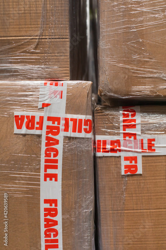 A stock photo close up of cardboard packages wrapped in the protective foil and fragile adhesive warning tape photo