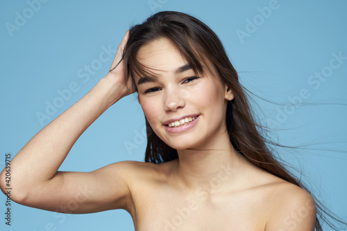 Pretty woman naked shoulders hair care close-up bank blue background
