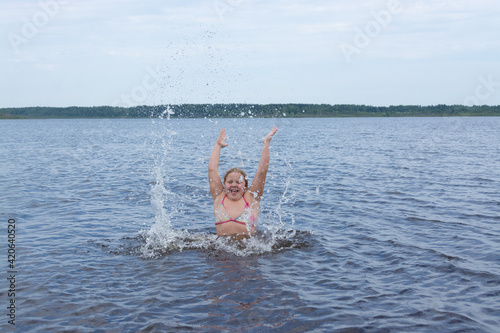 The girl frolics in the water on a hot sunny summer day and is happy. Kuvshinovo, Tver region, Russia. photo