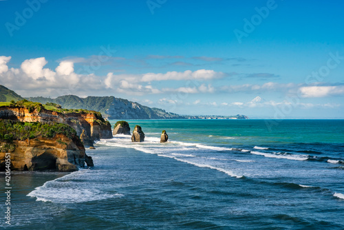 Amazing Rock formations the three sisters on Tongaporutu beach lined by huge cliffs  and the volcanic mountain in the background photo