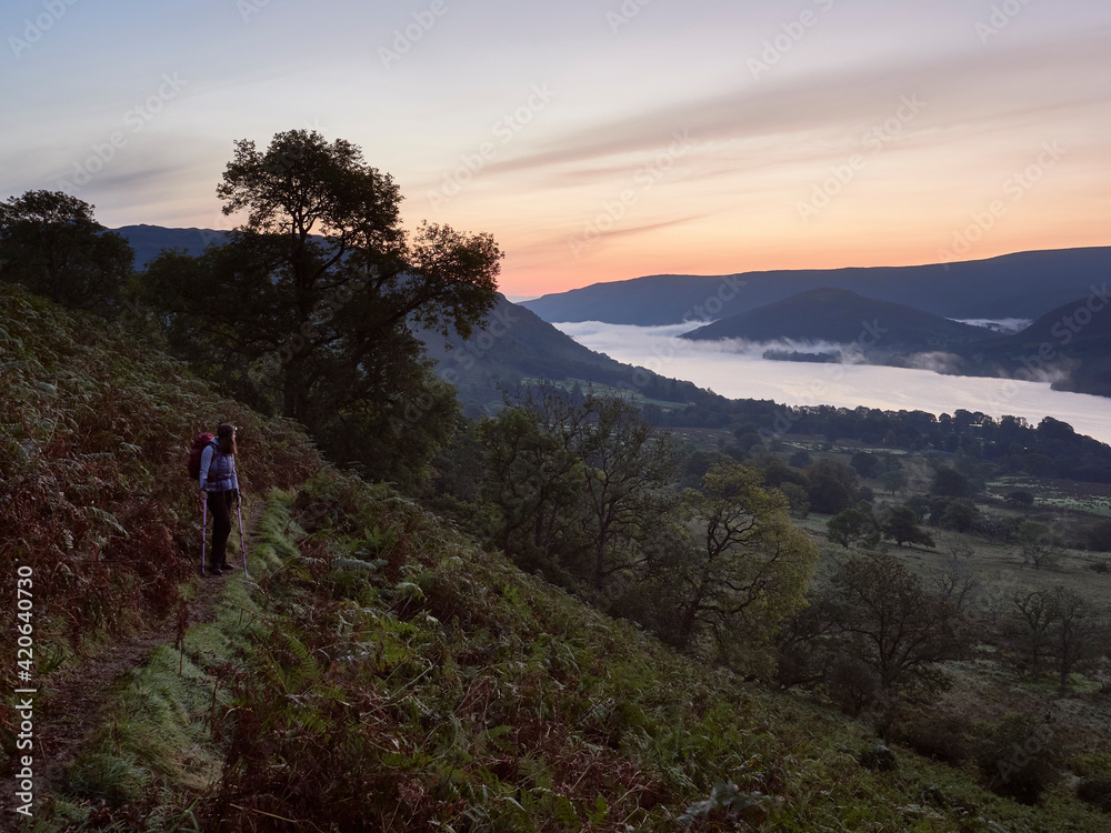 Female walking above Ullswater at dawn twilight. Lake District, UK. Female walking above Ullswater at dawn twilight. Lake District, UK.