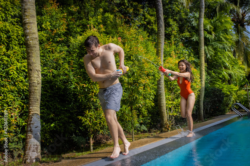 Two friends chasing each other with water guns shooting at each other.