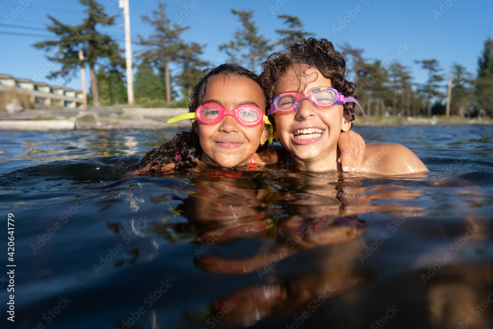 Brother and sister up to neck in water smile at the camera Brother and sister up to neck in water smile at the camera