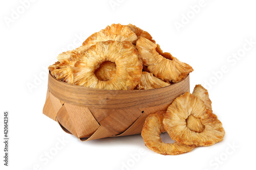 Tasty slices of dried pineapple in a basket isolated on white
