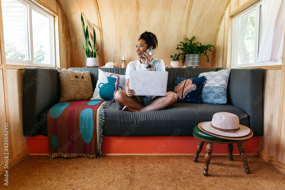 A young woman working from home on the couch using a laptop. A young woman working from home on the couch using a laptop.