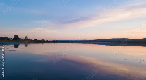 Cloudy sundown sky reflecting in calm lake photo