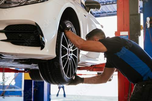 Adult mechanic changing tire to car