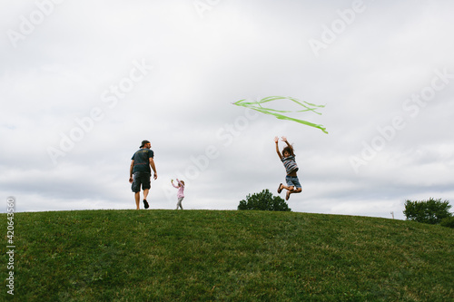 kids flying kite on a hill photo