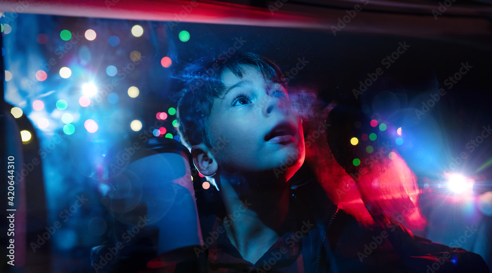 Young boy looking out the car window at christmas lights in amazement Young boy looking out the car window at christmas lights in amazement
