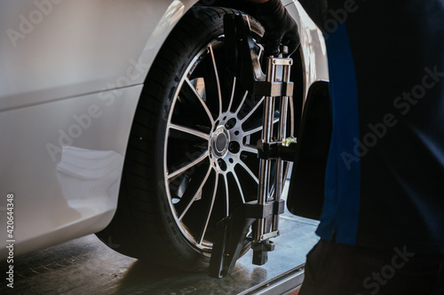 Adult mechanic using device in tire of car photo