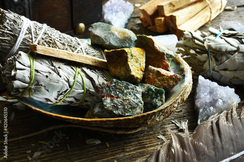 A close up image of sage smudge sticks and healing crystals in an abalone shell.