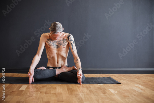 Tattooed man doing respiratory exercise and meditating photo