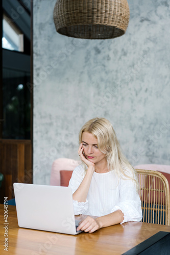 Thoughtful woman working with laptop at home photo