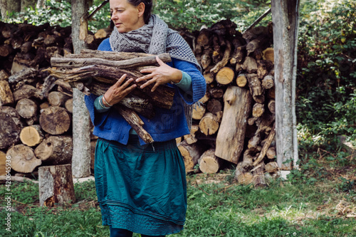 mature woman carrying wood for burning photo