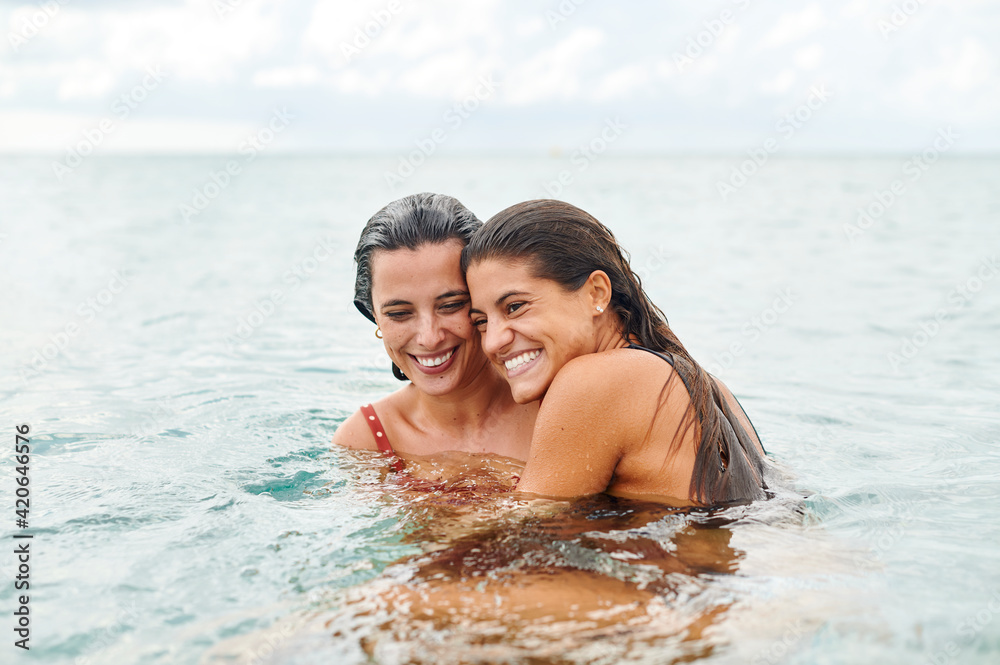 Two female friends hugging in the ocean Two female friends hugging in the ocean