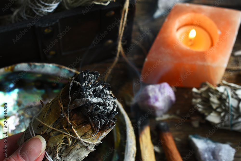 A close up image of a burning white sage smudge stick and healing crystals. A close up image of a burning white sage smudge stick and healing crystals.
