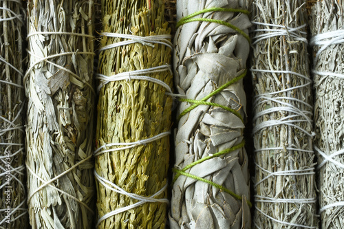 A top view image of several healing sage smudge bundles on burlap fabric. 