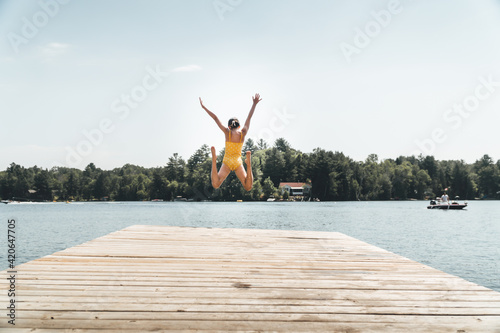 Girl jumping off pier into a lake photo